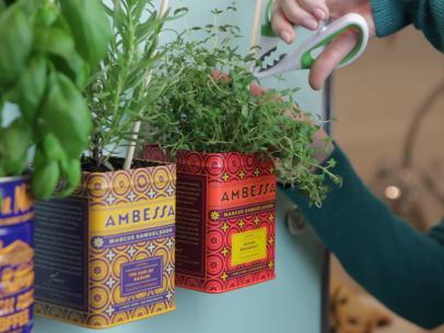 Several metal tea containers, repurposed to be planters, are held onto a refrigerator with magnets